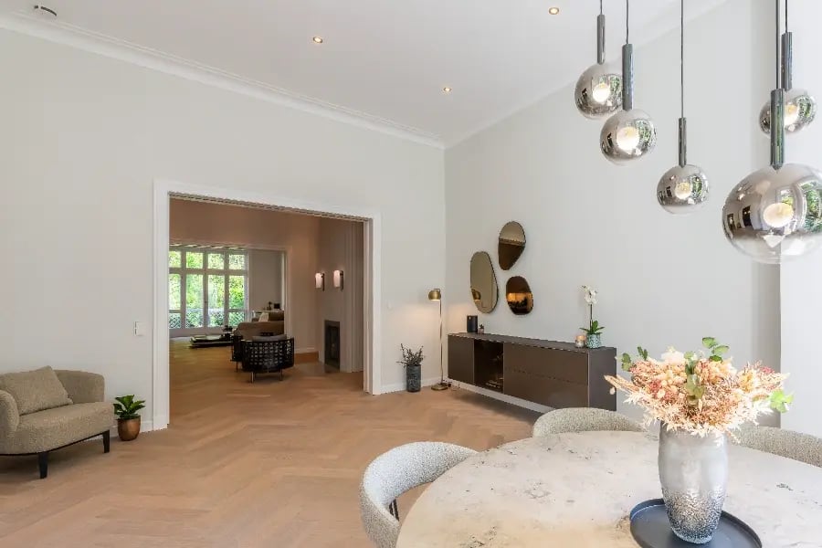 Altbausanierung Hamburg-Rotherbaum: heller Wohn/Essbereich mit Fischgrätparkett, Pendelleuchten und Blick in den Salon.