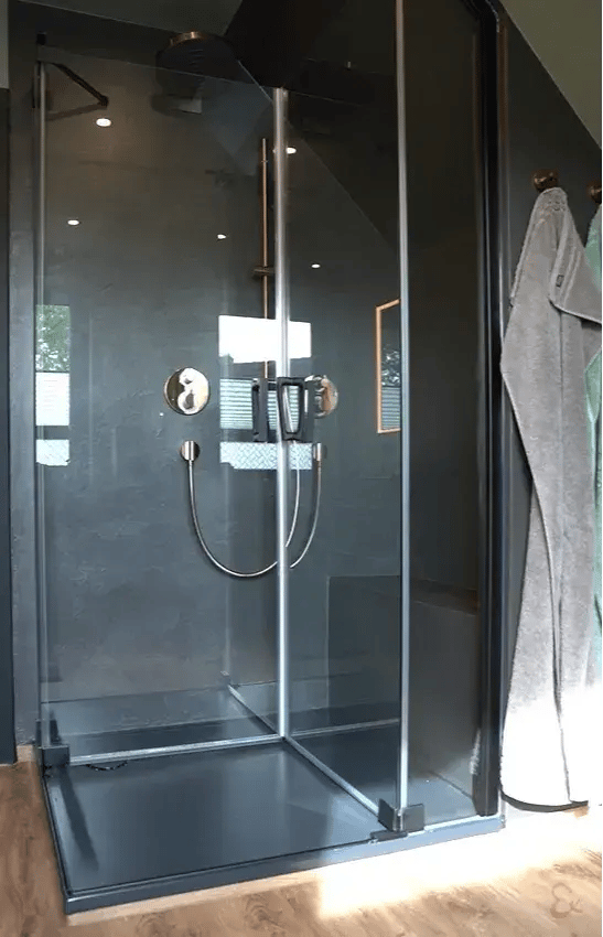Fugenloses Bad unter der Dachschräge in Buxtehude mit dunklen Wänden und großer Glasdusche