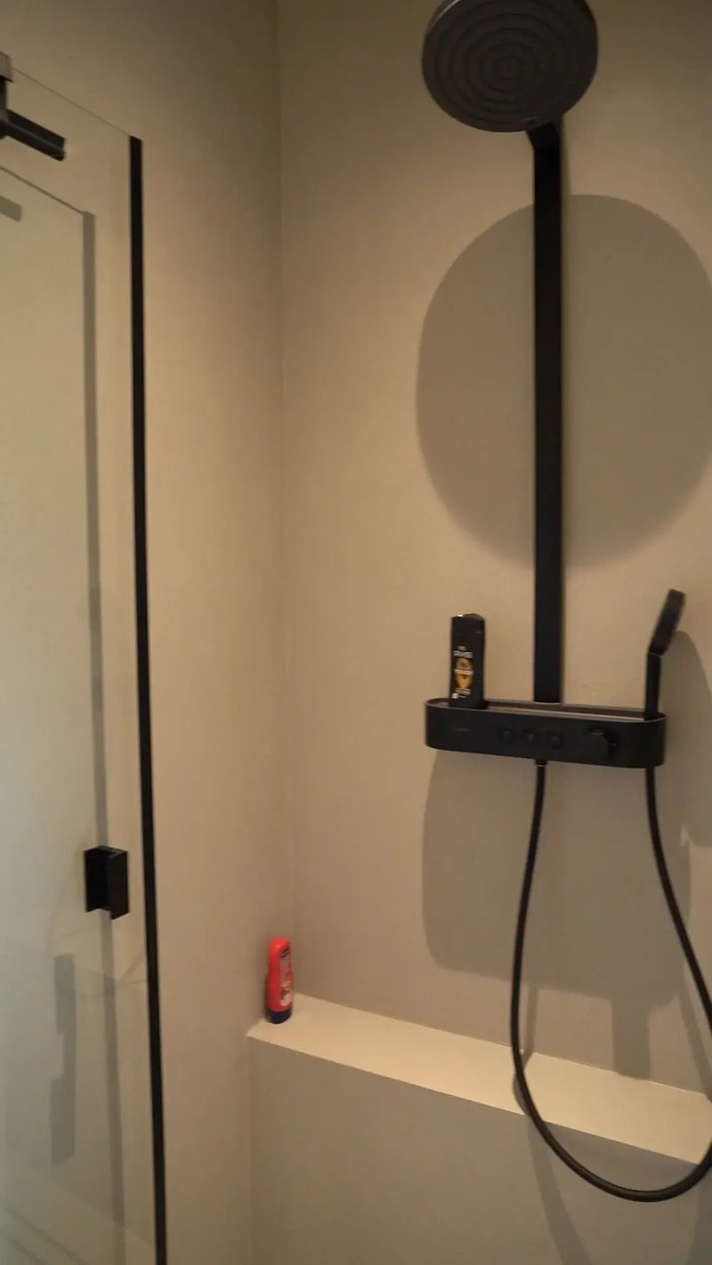 Dusche mit fugenloser Wand, schwarzer Regenbrause und Ablage im Neubau in Horneburg