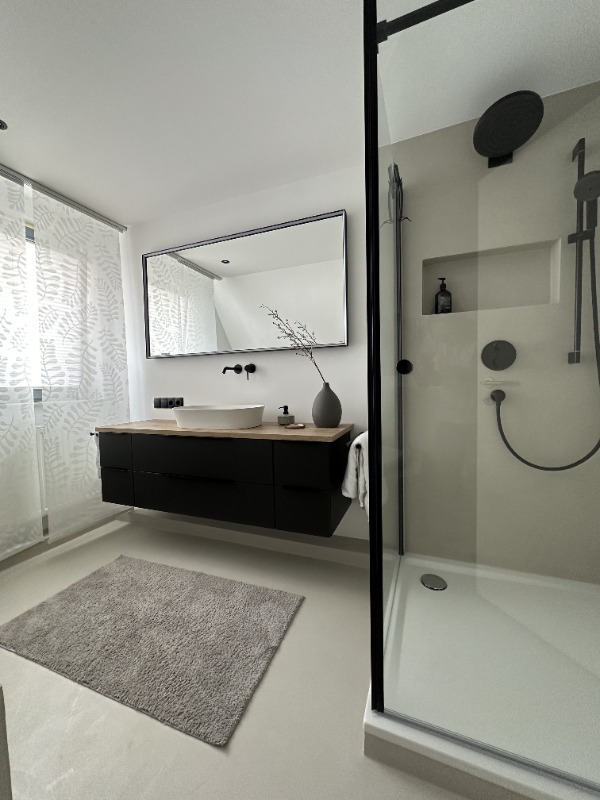 Fugenloses Bad in Beige mit schwarzer Dusche und Waschtisch
