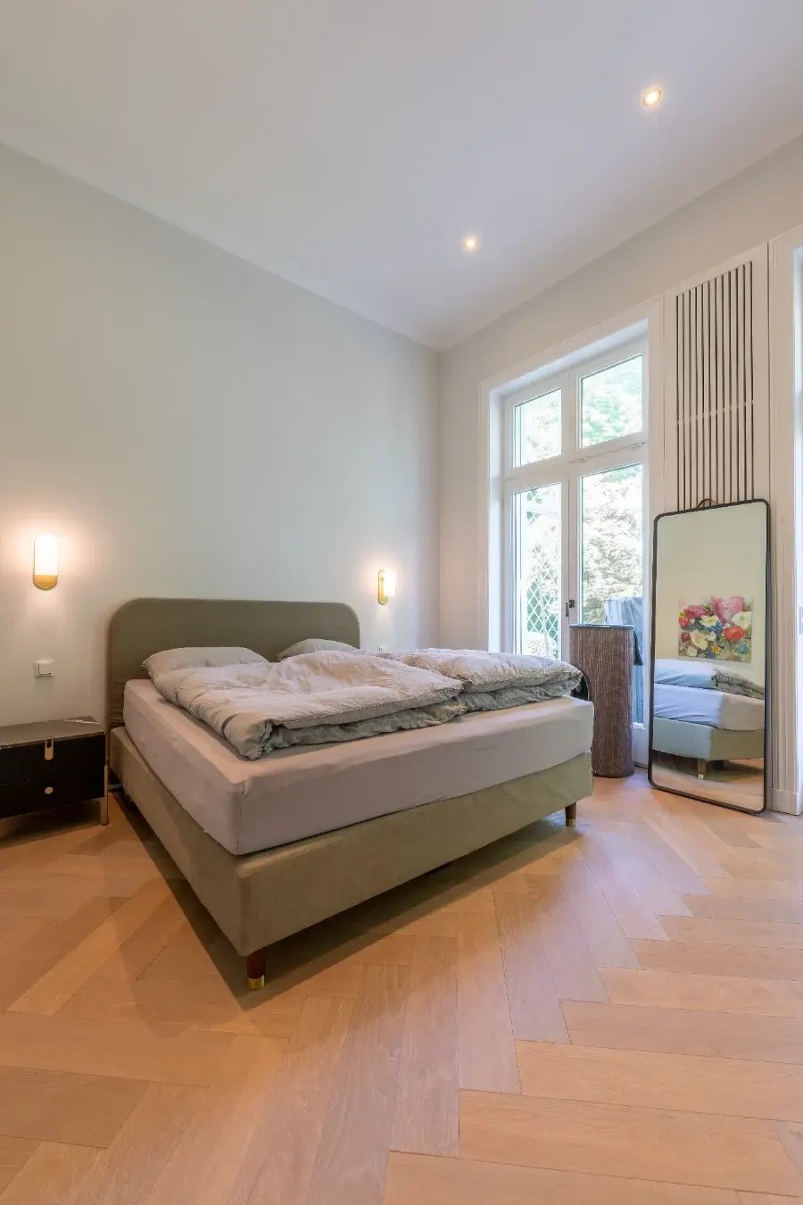 Hamburg-Rotherbaum: Gesunde Wandflächen im Altbau – helles Schlafzimmer mit glatten Wänden, Fischgrätparkett und Balkontür.