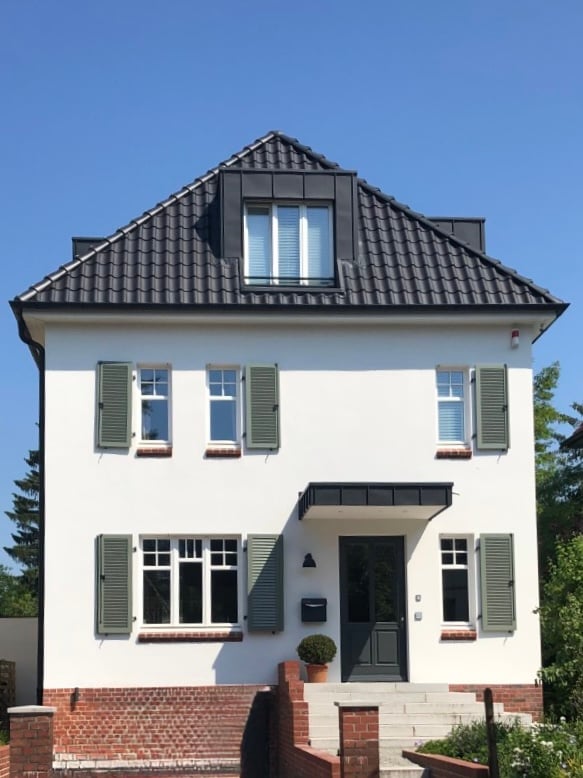 Kaffeemühlen-Haus mit frisch gestrichener weißer Fassade und grünen Fensterläden