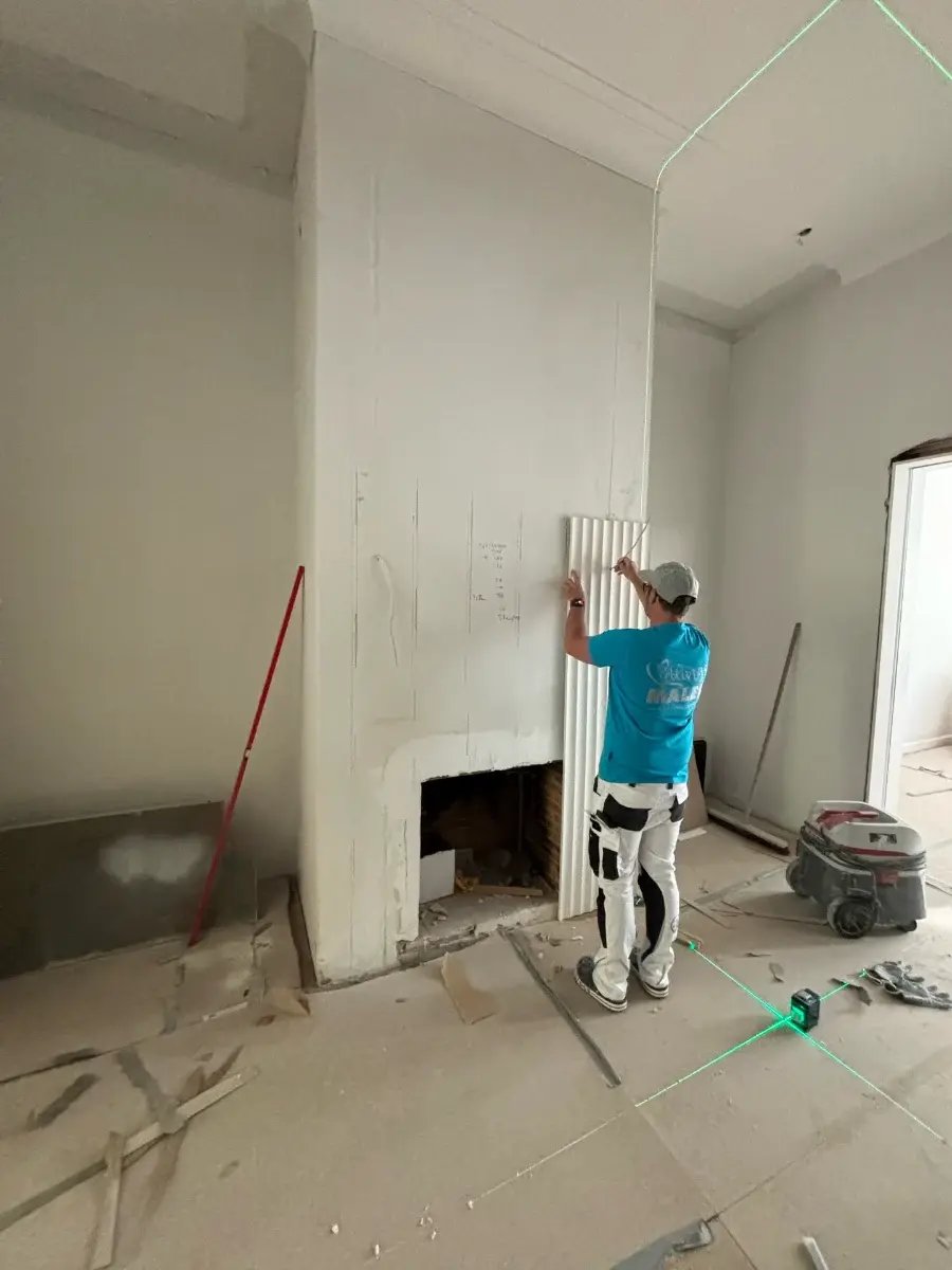 Maler richtet die Kaminverkleidung im Altbau mit dem Laser aus