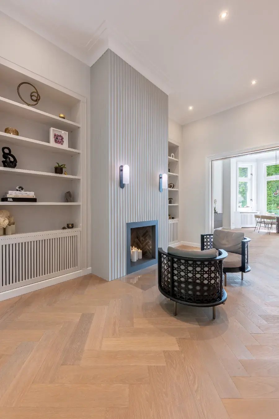 Altbausanierung Hamburg-Rotherbaum: Kaminwand mit Lamellen, Einbauregale, Fischgrätparkett, Blick ins Erker-Esszimmer.