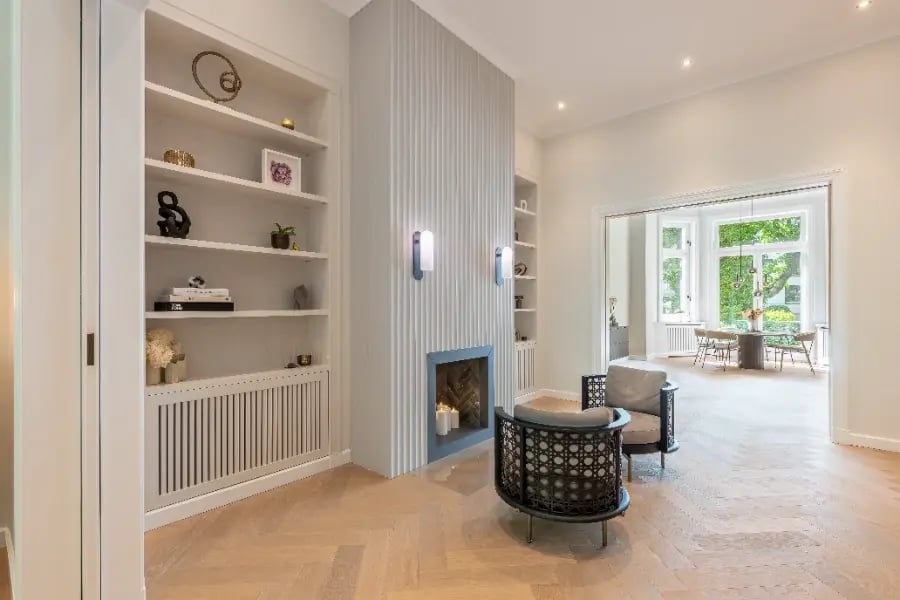 Altbausanierung Hamburg-Rotherbaum: Kaminwand mit Profilleisten, Einbauregale, Fischgrätparkett, Durchgang zum Erker.