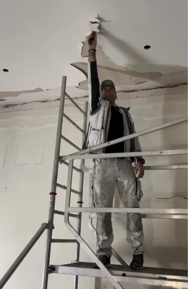 Maler öffnet eine lose Deckenbeschichtung im Altbau