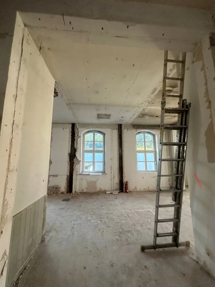 Alte Post vor der Sanierung: offener Rohbau mit Leiter und Bogenfenstern