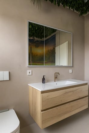 Modernes Badezimmer mit schwebendem Holzwaschtisch, fugenlos gespachtelter Wand in Naturton und beleuchtetem Spiegel mit Sonnenuntergangsreflexion – kombiniert mit stilvollem Wandbewuchs an der Decke.