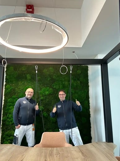 Marko Keßling und Frank Sinning, Geschäftsführer von K&amp;S Farbkonzepte, im modernen Besprechungsraum vor einer grünen Mooswand.