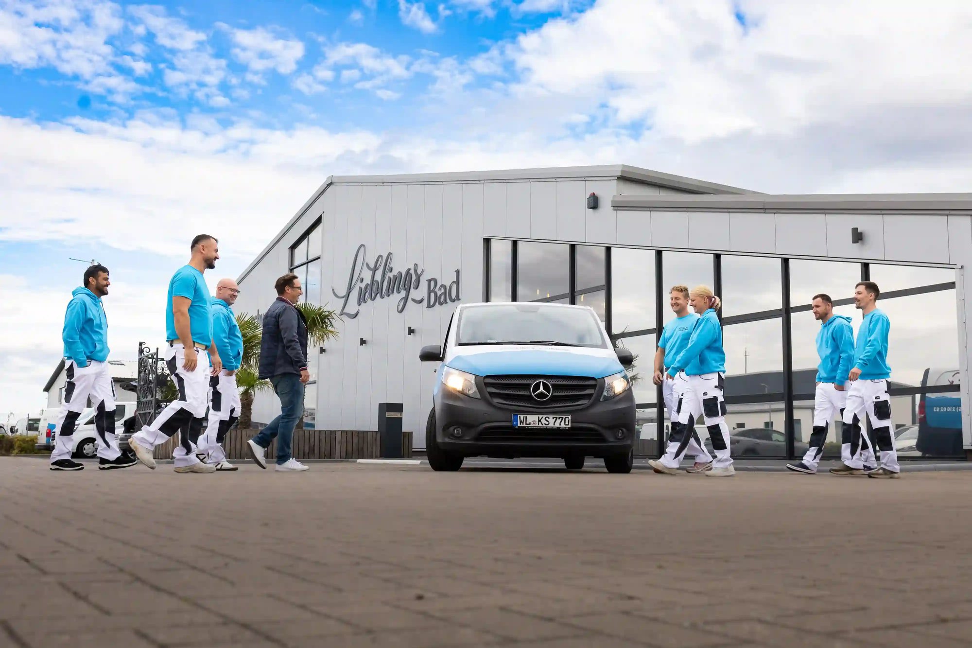 Das Team von KS Farbkonzepte vor dem Firmenfahrzeug und dem Gebäude „Lieblingsbad“ – vereint in moderner Arbeitskleidung, bereit für den nächsten Auftrag.