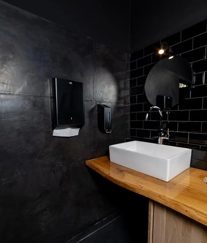 Die modernen WCs im Kliemannsland: Wände in extra dunkel angemischter Sichtbetonoptik (Kalkmarmorputz) kombiniert mit einem fugenlosen Boden. Stylisch, robust und extrem pflegeleicht – das K&amp;S Konzept für stark frequentierte Bereiche.