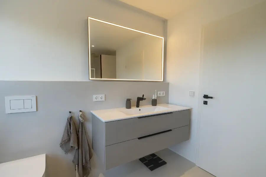 Fugenloser Boden in Betonoptik: nahtloser Look, pflegeleicht; mit LED-Spiegel und schwebendem Waschtisch in modernem Grau.