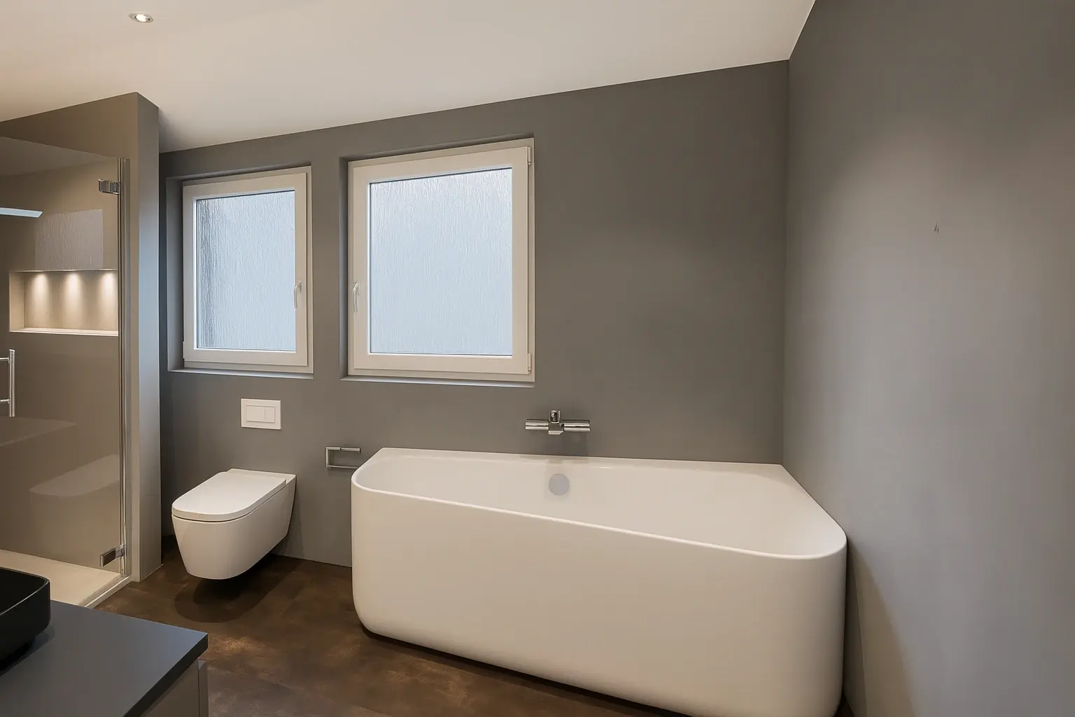 Modernes Bad: graue, fugenlose Wände, freistehende Wanne, Wand-WC, zwei satinierte Fenster und Walk-in-Dusche mit LED-Nische.