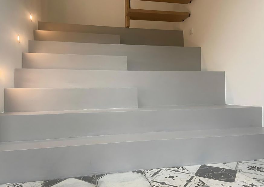 Fugenlose Treppe in Grau: robuste Mikrozement-Beschichtung mit integrierten Wandspots – nahtlos, modern, pflegeleicht.